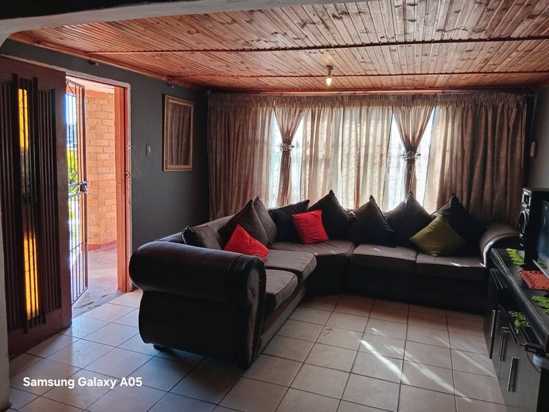 A living room featuring tiled flooring and a timber tongue and groove ceiling, with direct access to an outdoor area via a security gate.
