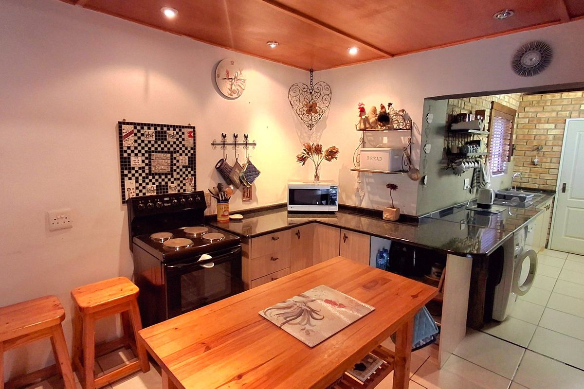 Functional kitchen featuring dark granite countertops, built-in cabinetry, and an electric stove, with an adjacent utility area and tiled flooring throughout.
