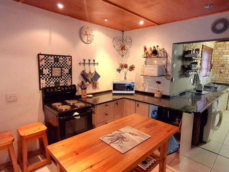 Functional kitchen featuring dark granite countertops, built-in cabinetry, and an electric stove, with an adjacent utility area and tiled flooring throughout.