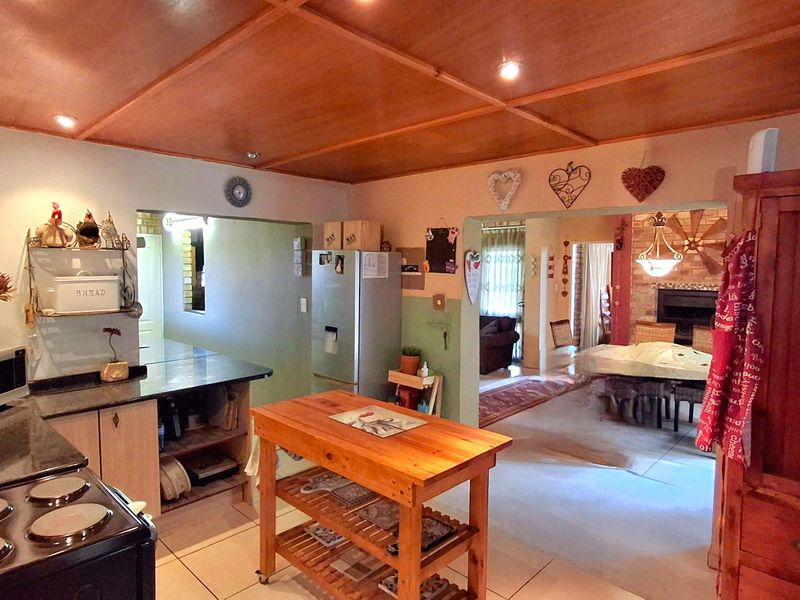 Open-plan kitchen area featuring stone countertops, electric stove, and wooden panelled ceilings, flowing into the adjacent living and dining spaces.