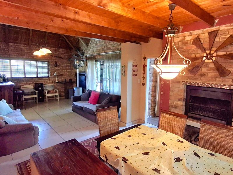 Spacious open-plan living and dining area featuring exposed timber beams, rustic brick walls, and a built-in fireplace, creating a warm and character-filled atmosphere.