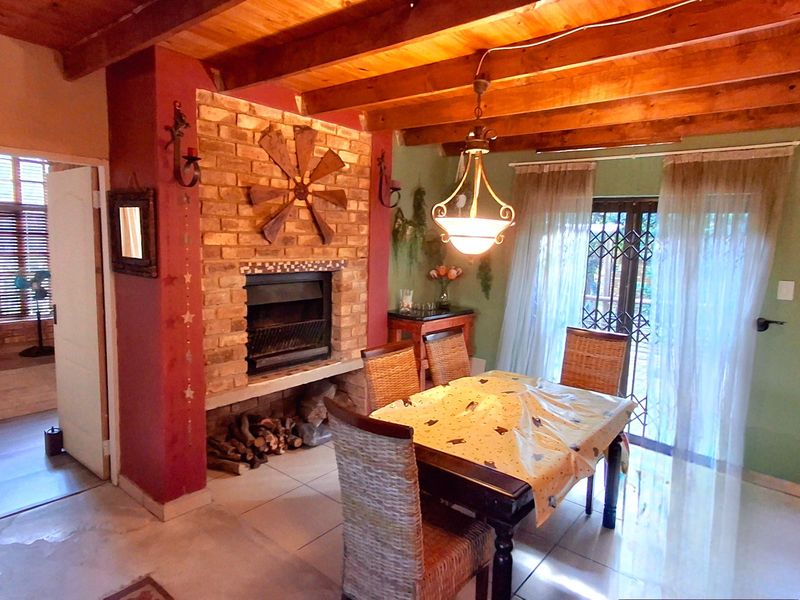 Dining area featuring exposed timber ceiling beams, a prominent brick fireplace, and direct access to the outdoors through sliding glass doors.
