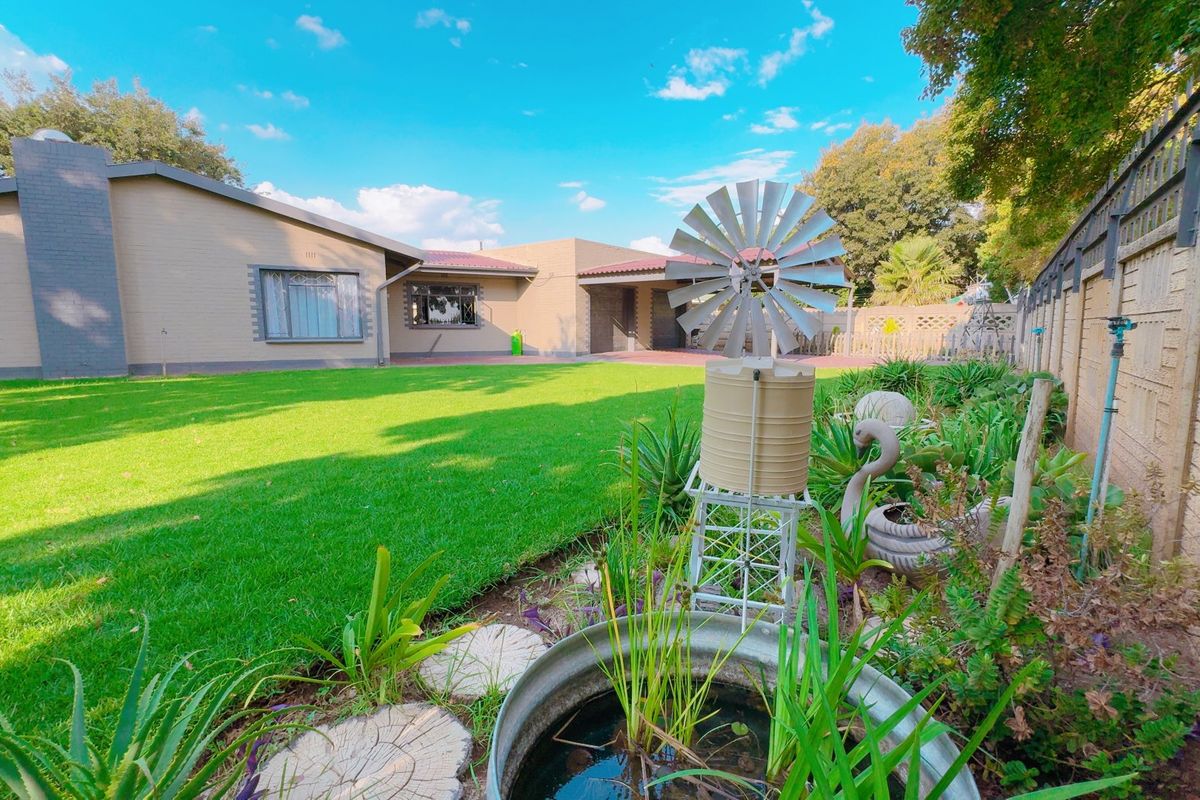 A spacious rear garden featuring a well-maintained lawn, paved areas, and a brick boundary wall, providing a private outdoor space for the home.