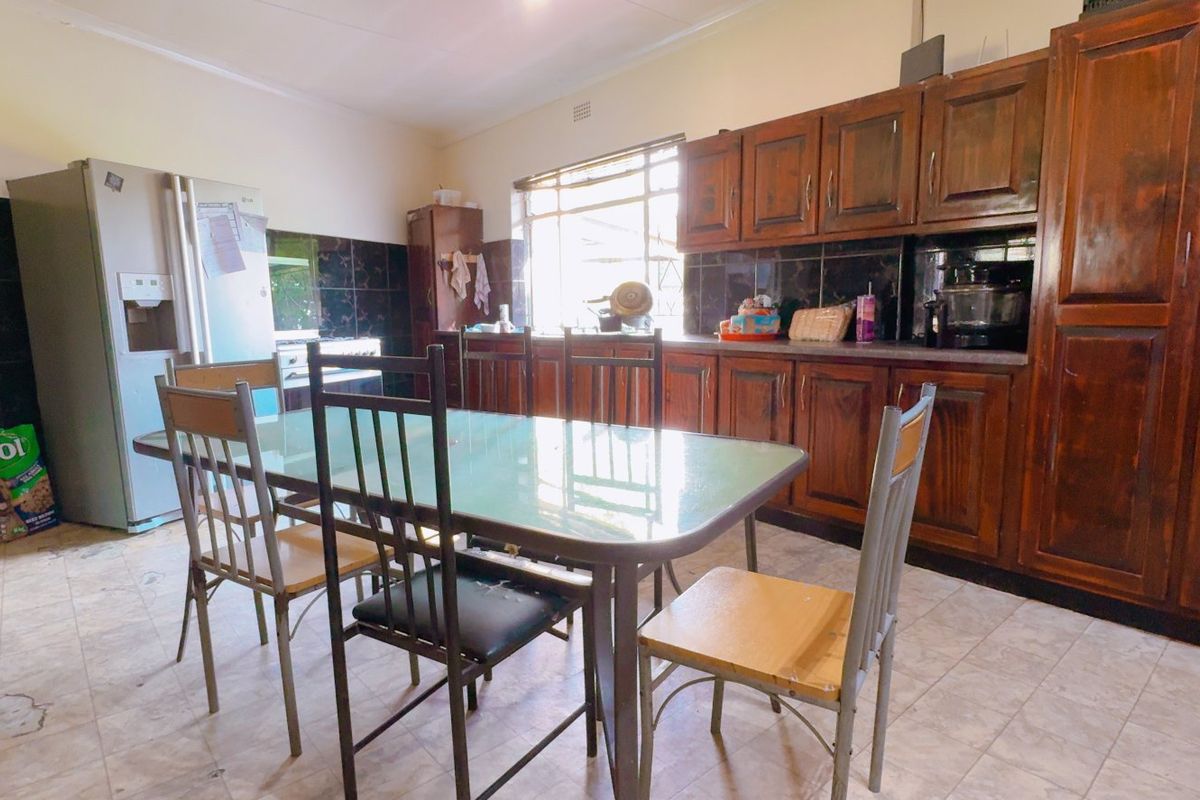 A spacious kitchen featuring extensive wooden cabinetry, tiled backsplash, and tiled flooring, offering a functional layout with ample storage space.