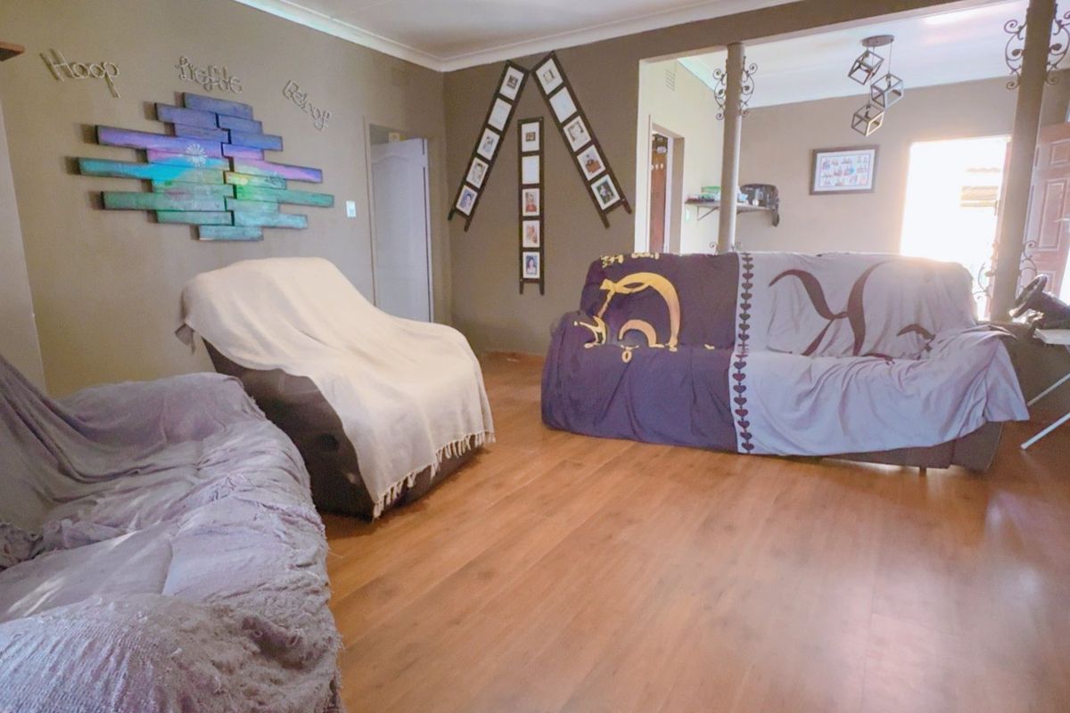 A living room area featuring laminate flooring and decorative support columns, providing an open layout with access to adjacent spaces.