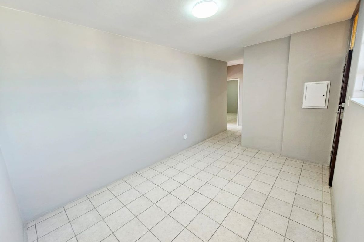 A bright, empty living area featuring neutral wall paint and ceramic floor tiles, providing a clean and versatile space for customization.