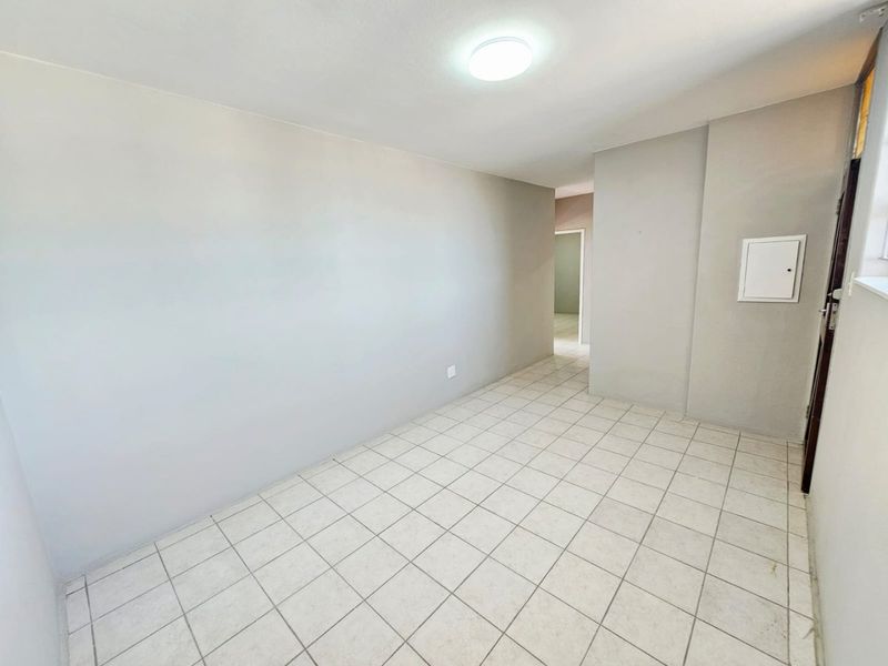 A bright, empty living area featuring neutral wall paint and ceramic floor tiles, providing a clean and versatile space for customization.