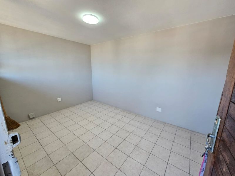 An empty bedroom featuring neutral wall paint, tiled flooring, and a central ceiling light fixture.