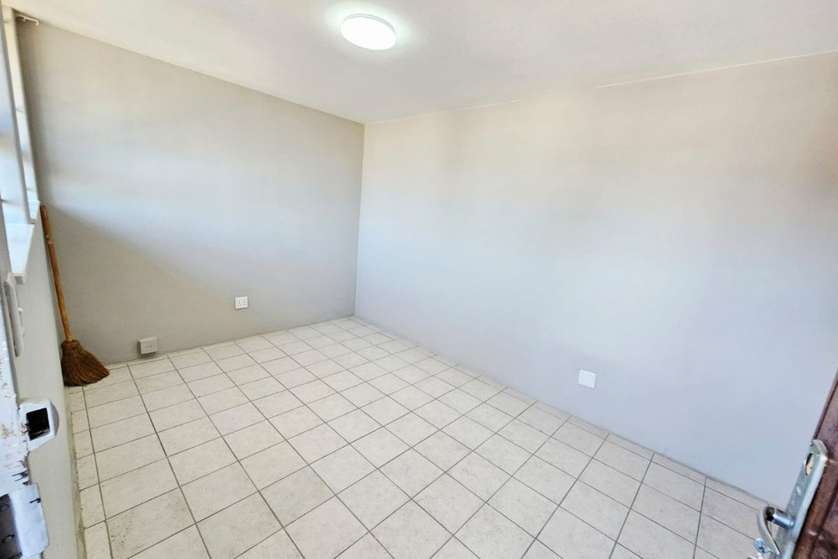 A vacant bedroom featuring neutral wall paint, tiled flooring, and a central ceiling light fixture, ready for personalization.
