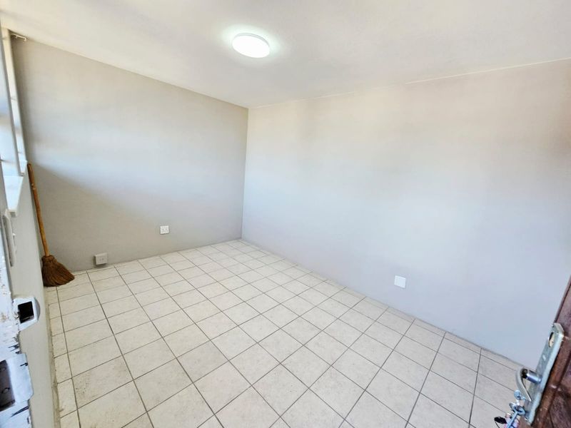 A vacant bedroom featuring neutral wall paint, tiled flooring, and a central ceiling light fixture, ready for personalization.