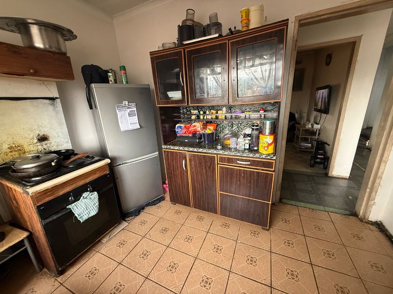 A functional kitchen featuring built-in cabinetry, granite countertops, and a built-in oven, with ceramic tile flooring throughout.
