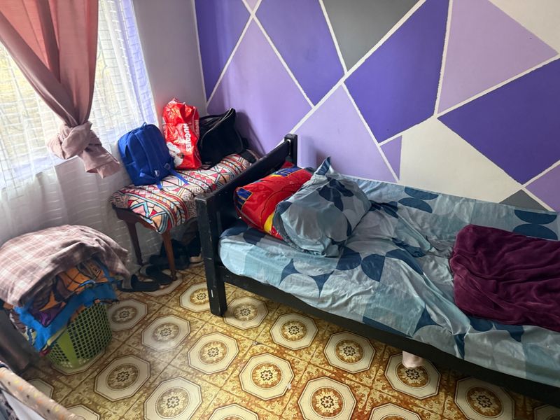 A bedroom featuring patterned vinyl flooring and a geometric accent wall, providing a functional space with potential for cosmetic updates.