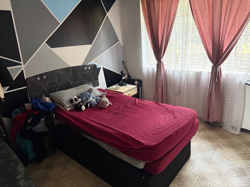 A bedroom featuring tiled flooring and a window fitted with security bars, finished with a geometric accent wall.