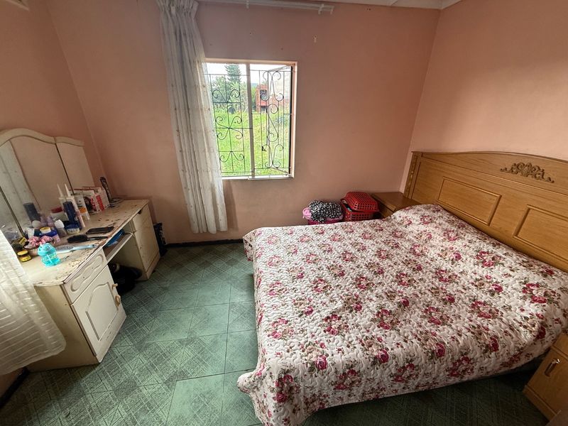 A bedroom featuring tiled flooring and a window with security bars, offering a functional space with potential for cosmetic updates.