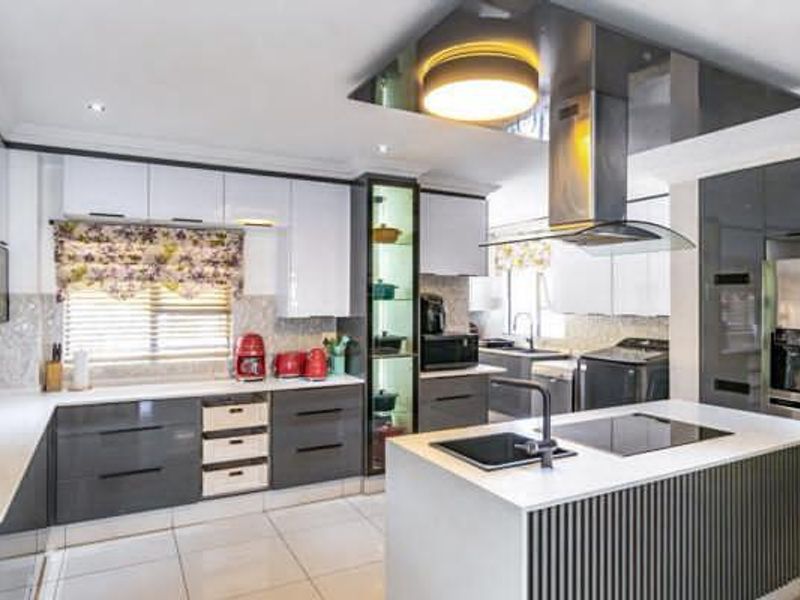 Modern kitchen featuring high-gloss cabinetry, a central island with an integrated hob and sink, and premium stainless steel extractor fan.
