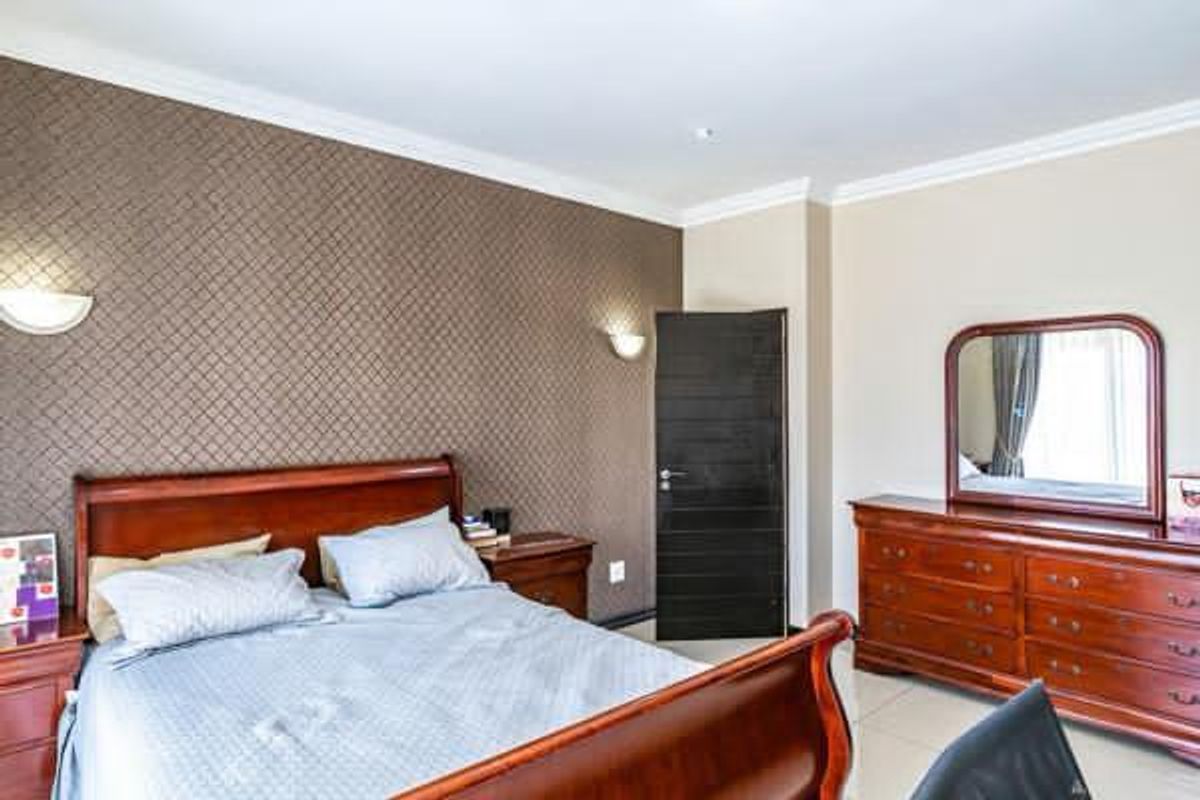 A well-maintained bedroom featuring textured accent wallpaper, wall sconces, and coving, providing a comfortable and finished living space.