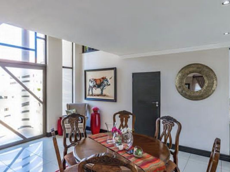 A bright dining area featuring large windows, tiled flooring, and recessed downlighting, creating an open and inviting space for meals.