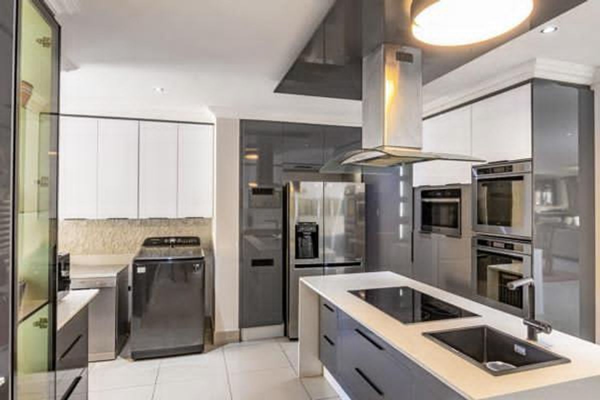 Modern kitchen featuring a central island with induction hob and sink, high-gloss cabinetry, and integrated stainless steel appliances.