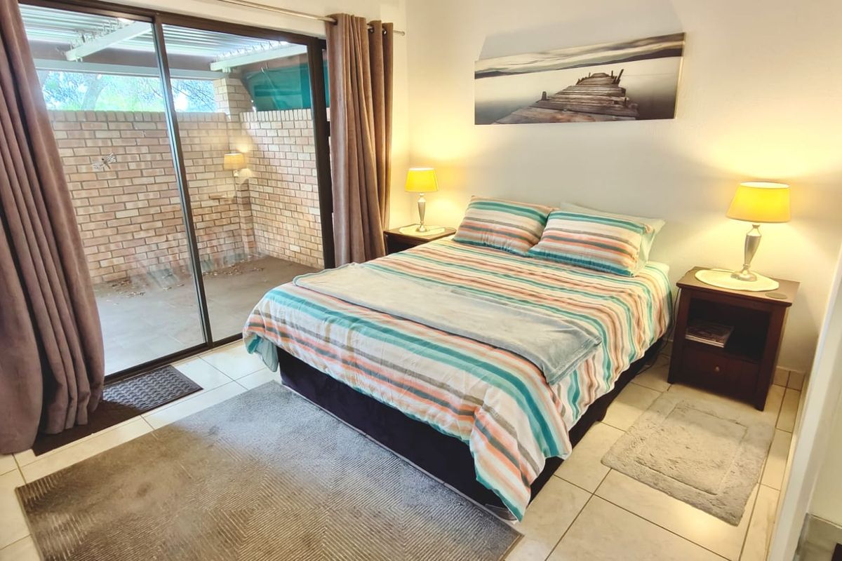A bedroom featuring tiled flooring and a large sliding glass door providing direct access to an outdoor patio area.