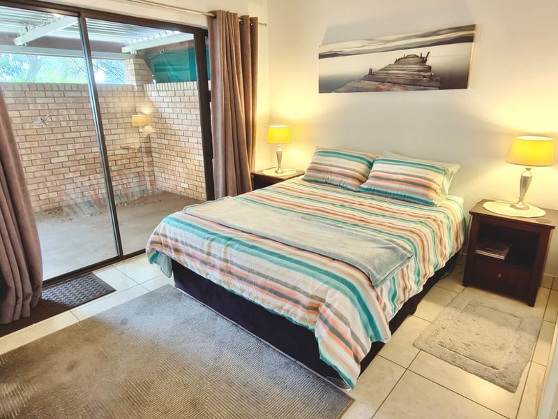 A bedroom featuring tiled flooring and a large sliding glass door providing direct access to an outdoor patio area.