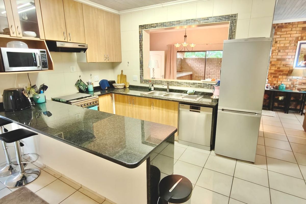 Functional kitchen featuring granite countertops, ample cabinetry, a double basin sink, and a convenient pass-through window connecting to the adjacent living area.