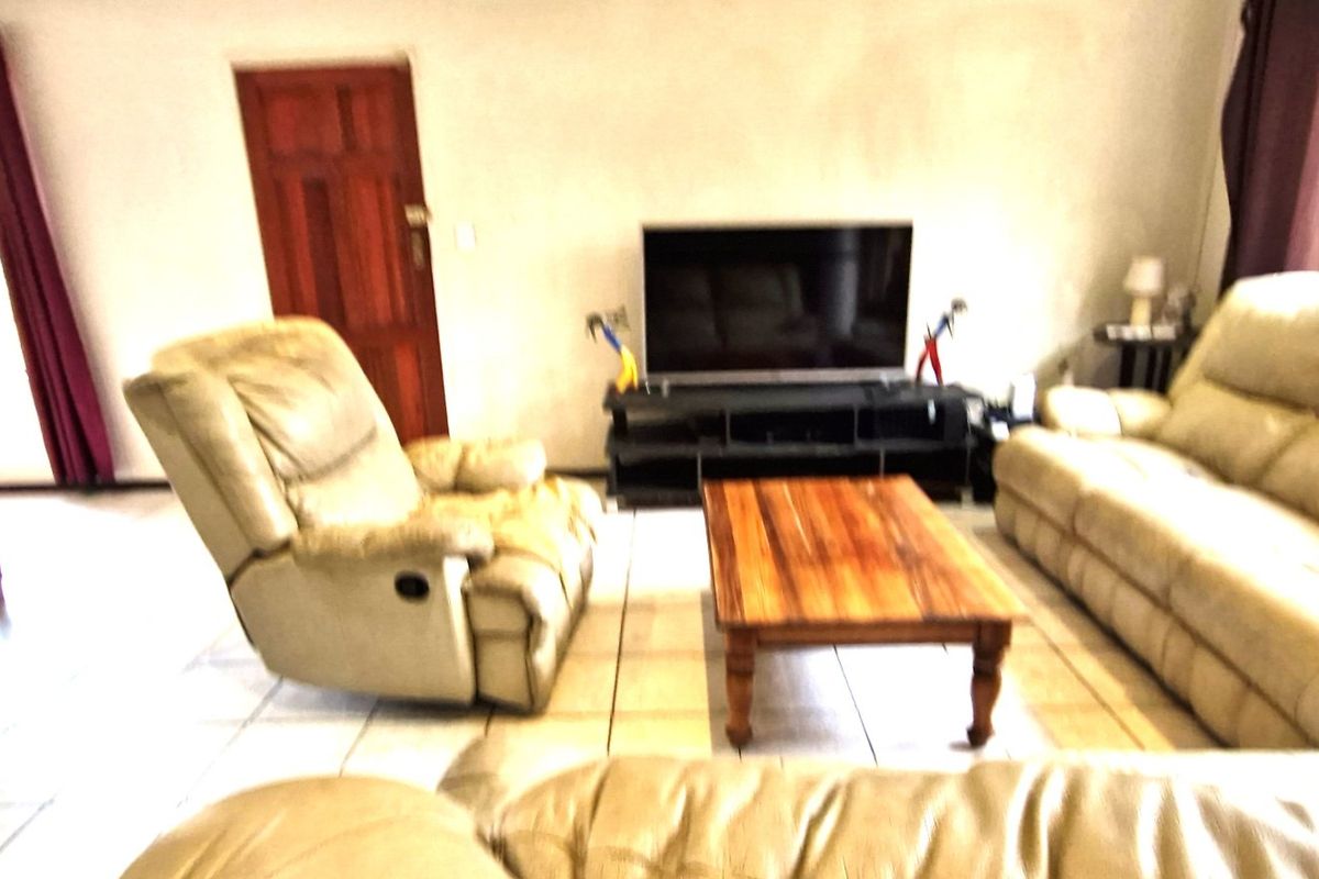 A living room area featuring tiled flooring and a wooden door, providing a functional space for relaxation.