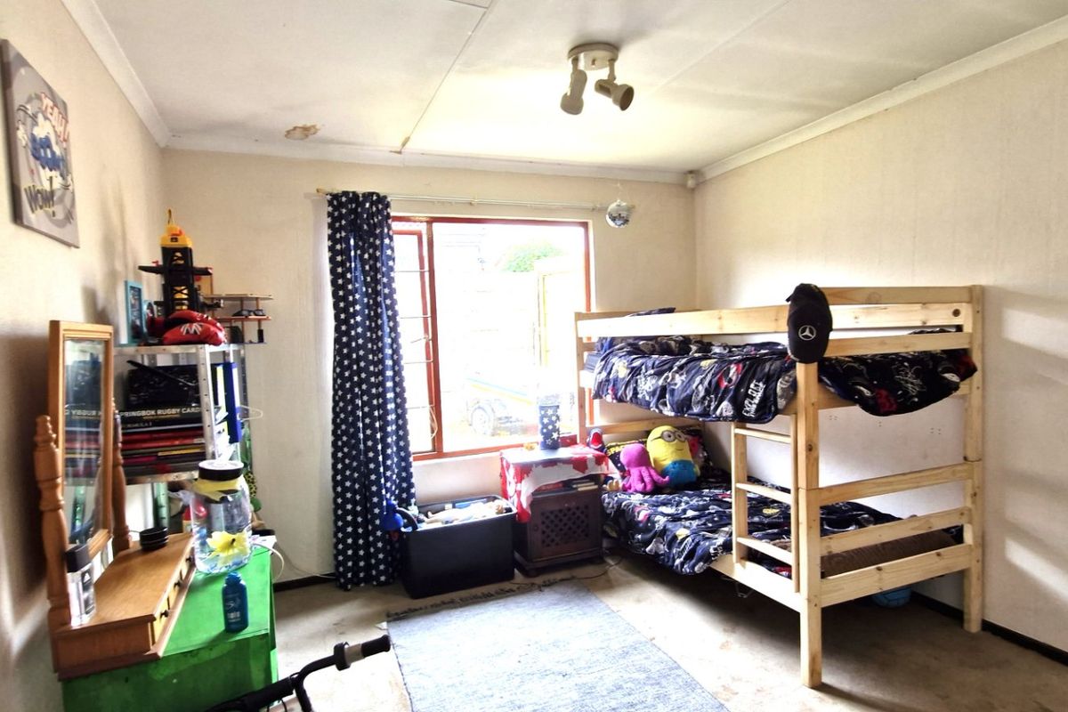 A bedroom featuring a window, ceiling light fixture, and coving, currently showing signs of wear and ceiling damage.