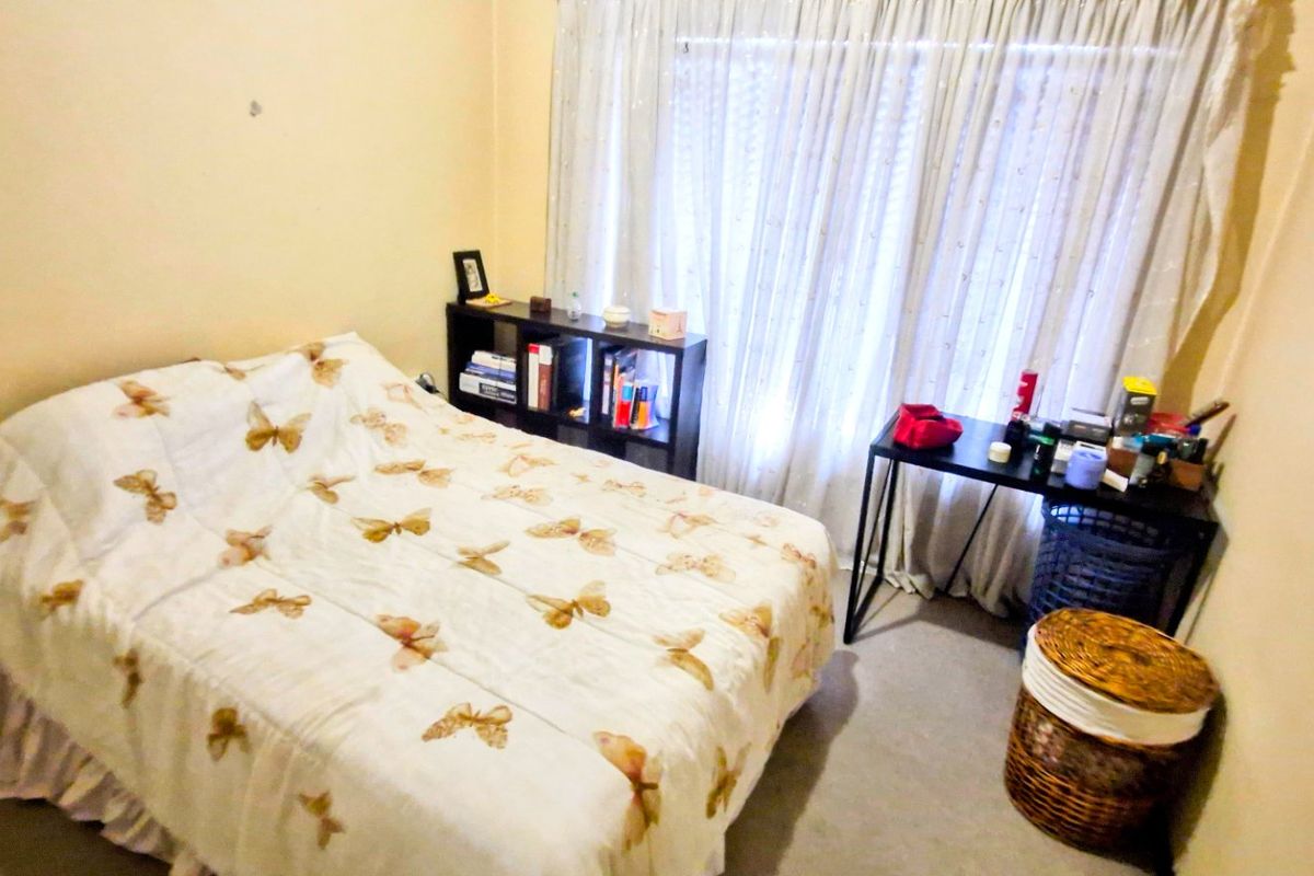 A compact bedroom featuring carpeted flooring and window treatments, requiring minor cosmetic updates to refresh the space.