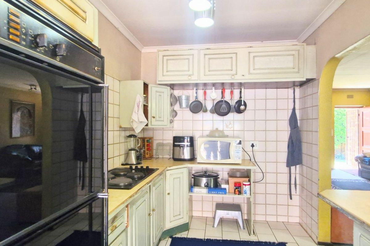 A dated kitchen featuring built-in oven, hob, and traditional cabinetry with tiled backsplash, offering potential for a modern renovation.