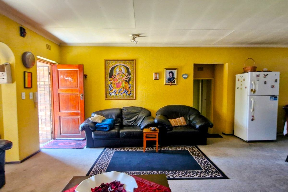 A spacious living area featuring yellow walls, an arched entryway, and built-in cabinetry, offering a functional layout with potential for modern updates.