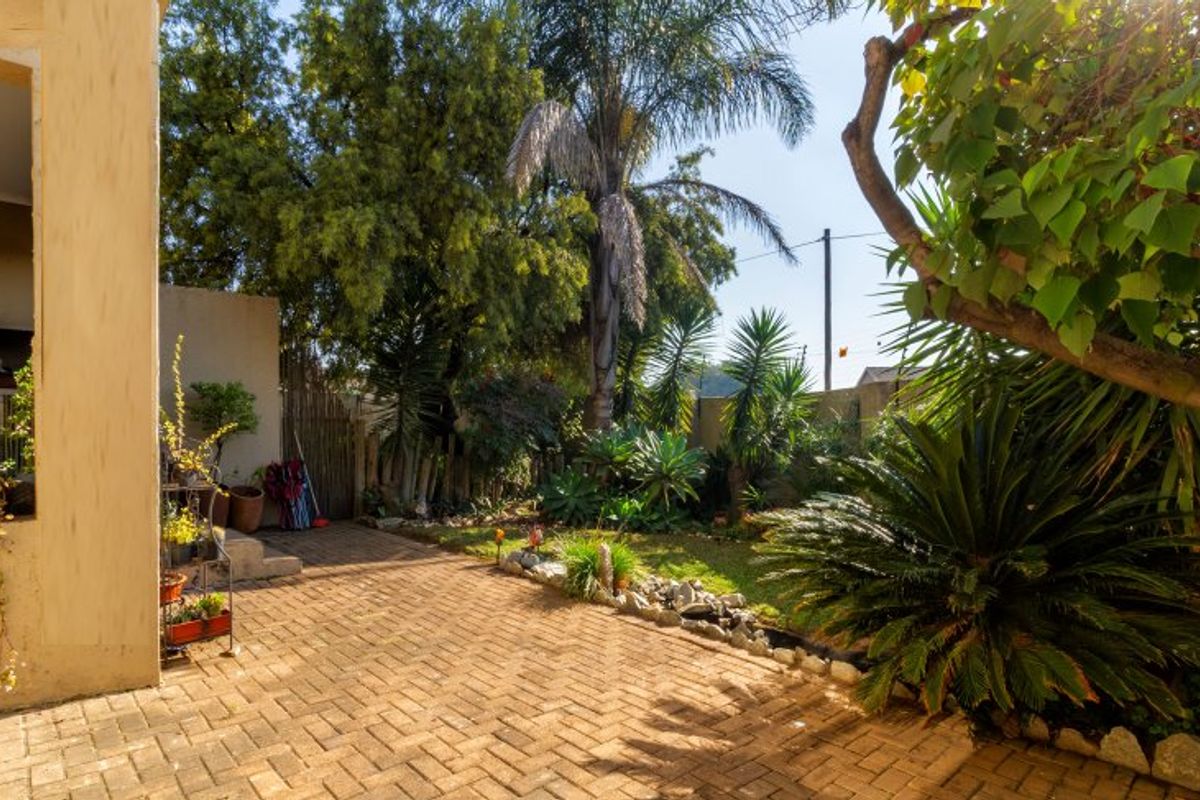 A private rear garden featuring brick paving, established landscaping, and a built-in braai area, offering a peaceful outdoor space.