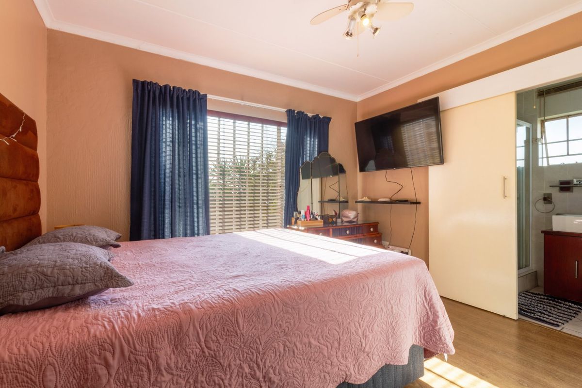 A bedroom featuring laminate flooring, a ceiling fan, and an en-suite bathroom access via a sliding door.