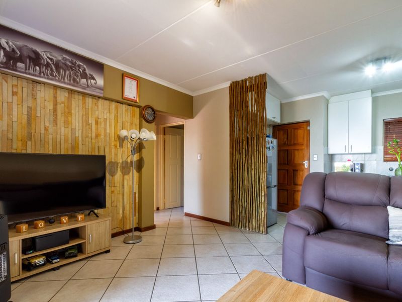 Open plan living area featuring a stone accent wall, ceramic tiled flooring, and a decorative bamboo room divider leading to the kitchen.