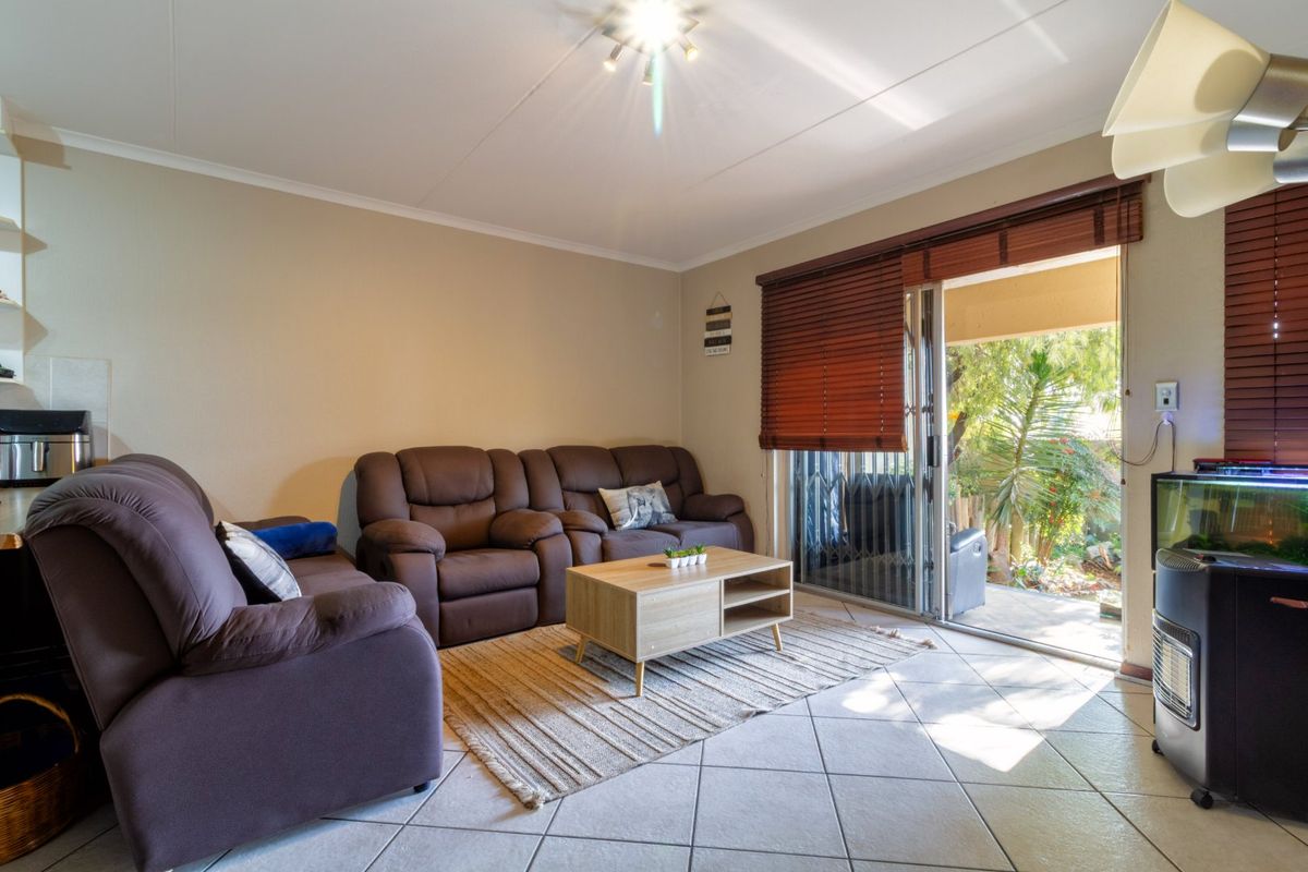 A comfortable living room featuring tiled flooring and a sliding glass door that provides direct access to an outdoor patio area.