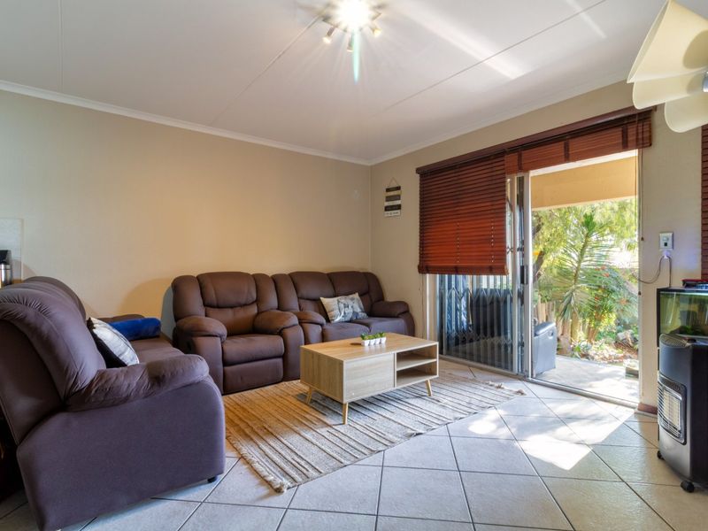 A comfortable living room featuring tiled flooring and a sliding glass door that provides direct access to an outdoor patio area.
