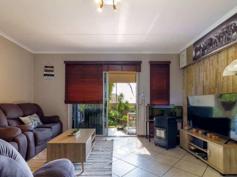 A comfortable living room featuring tiled flooring, a textured stone feature wall, and a sliding glass door providing access to an outdoor patio area.