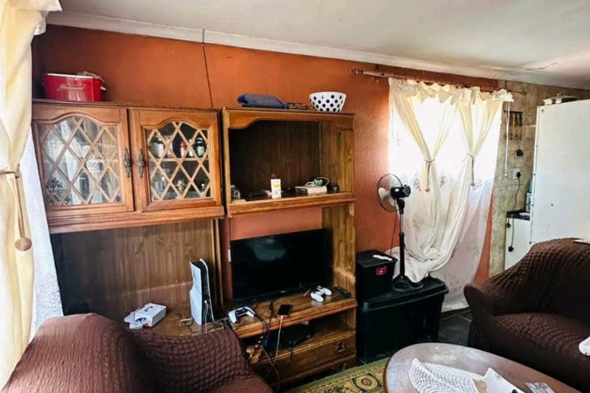 A living room area featuring a built-in wooden shelving unit and textured wall finishes, requiring cosmetic updates to improve the overall aesthetic.