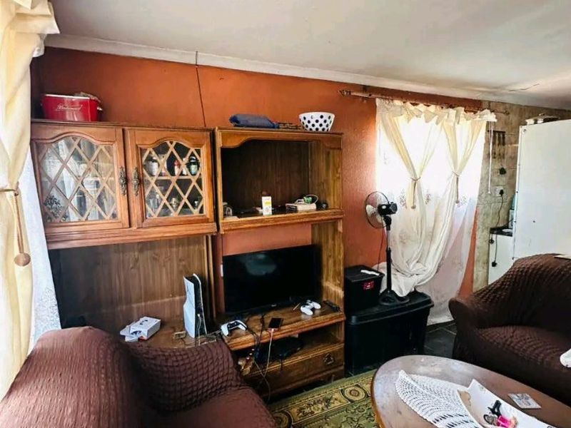 A living room area featuring a built-in wooden shelving unit and textured wall finishes, requiring cosmetic updates to improve the overall aesthetic.