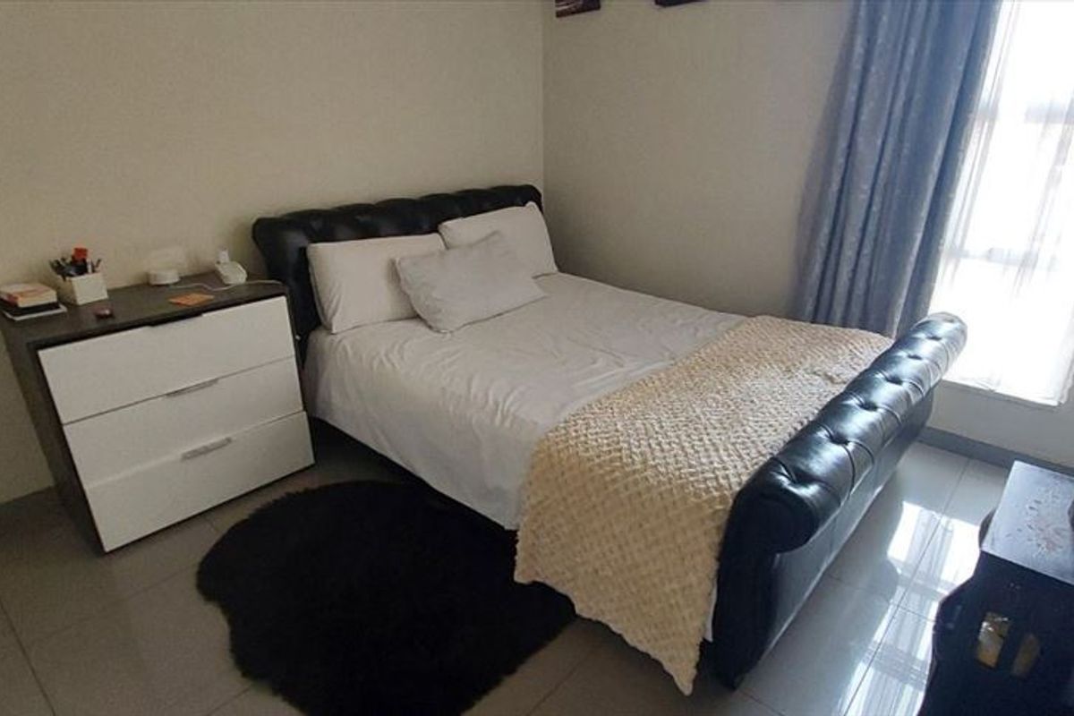 A functional bedroom featuring tiled flooring and a large window allowing for natural light.