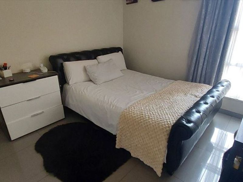 A functional bedroom featuring tiled flooring and a large window allowing for natural light.