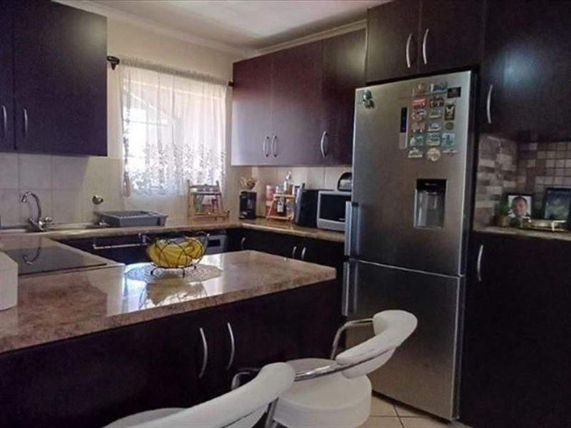 A functional kitchen featuring dark wood cabinetry, granite countertops, and a mosaic tile backsplash, providing a practical workspace for cooking and meal preparation.