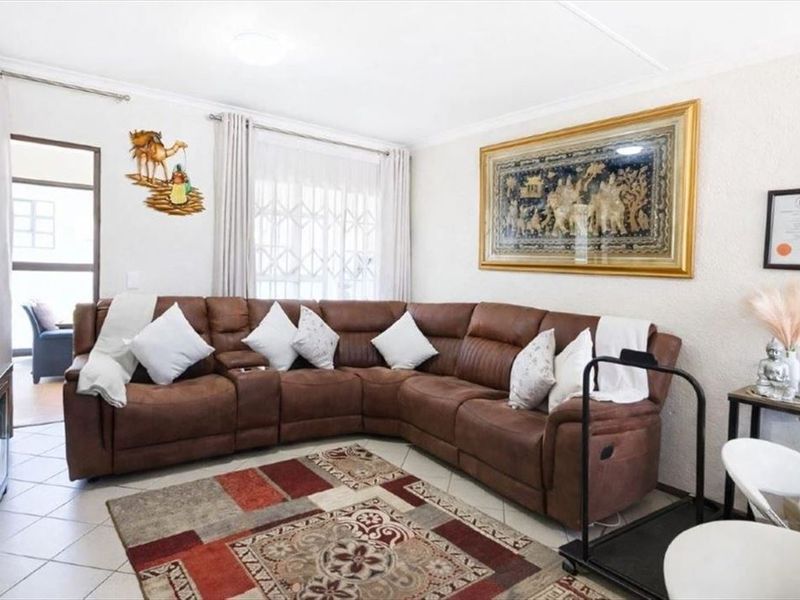 A comfortable living room featuring tiled flooring, a sliding door with security gate, and neutral wall finishes.