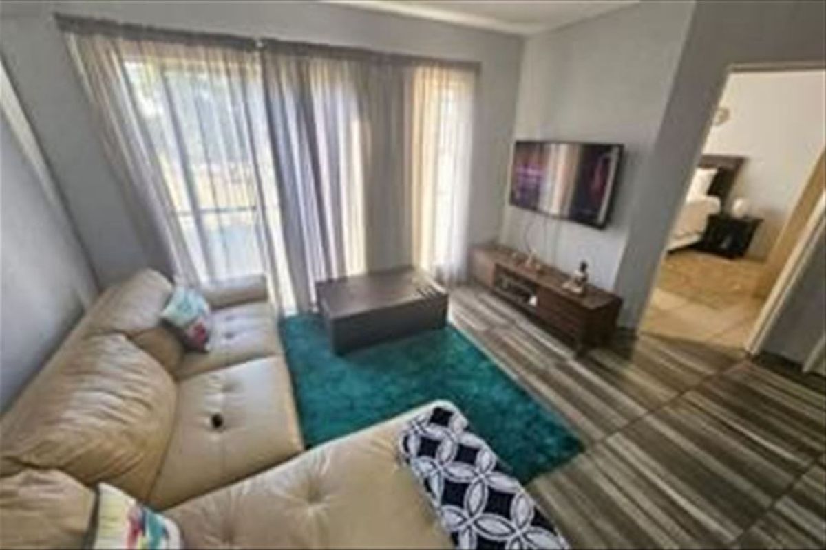 A living room featuring tiled flooring and a large sliding glass door providing natural light and access to the exterior.