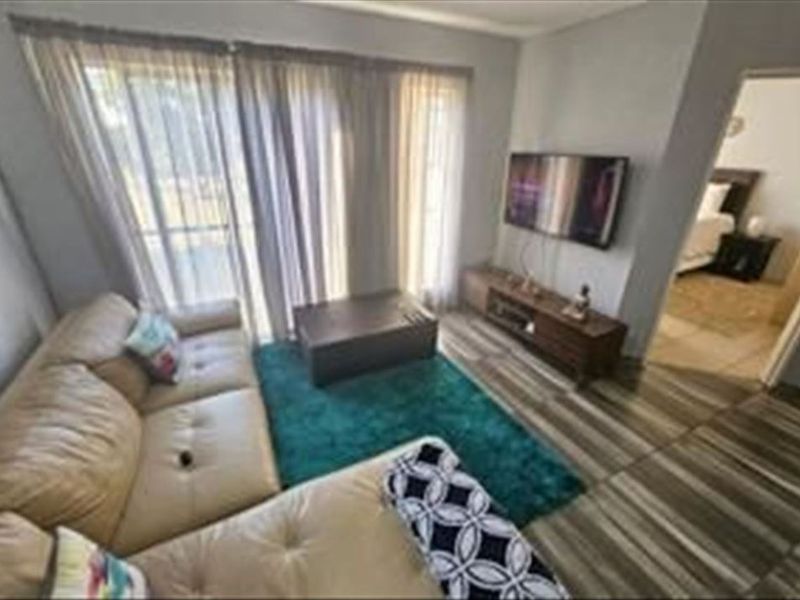 A living room featuring tiled flooring and a large sliding glass door providing natural light and access to the exterior.