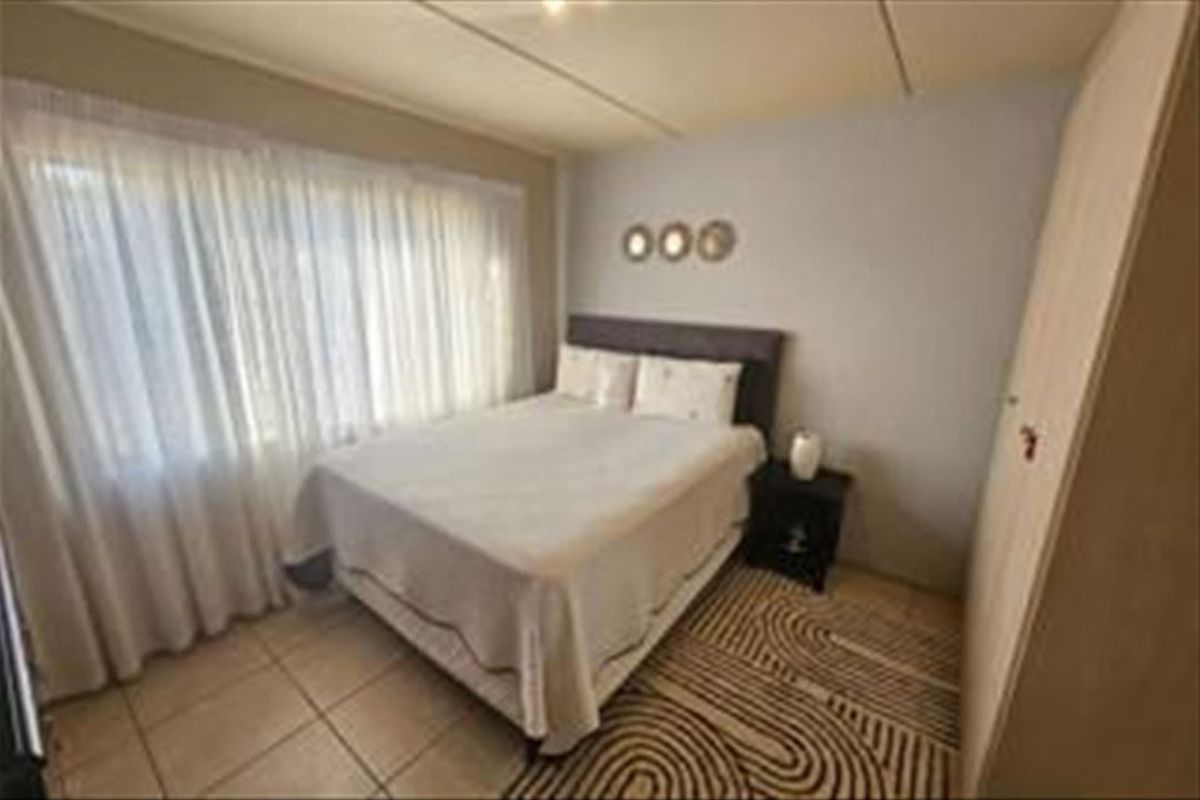 A functional bedroom featuring tiled flooring and a built-in wardrobe, offering a neutral space ready for personalization.