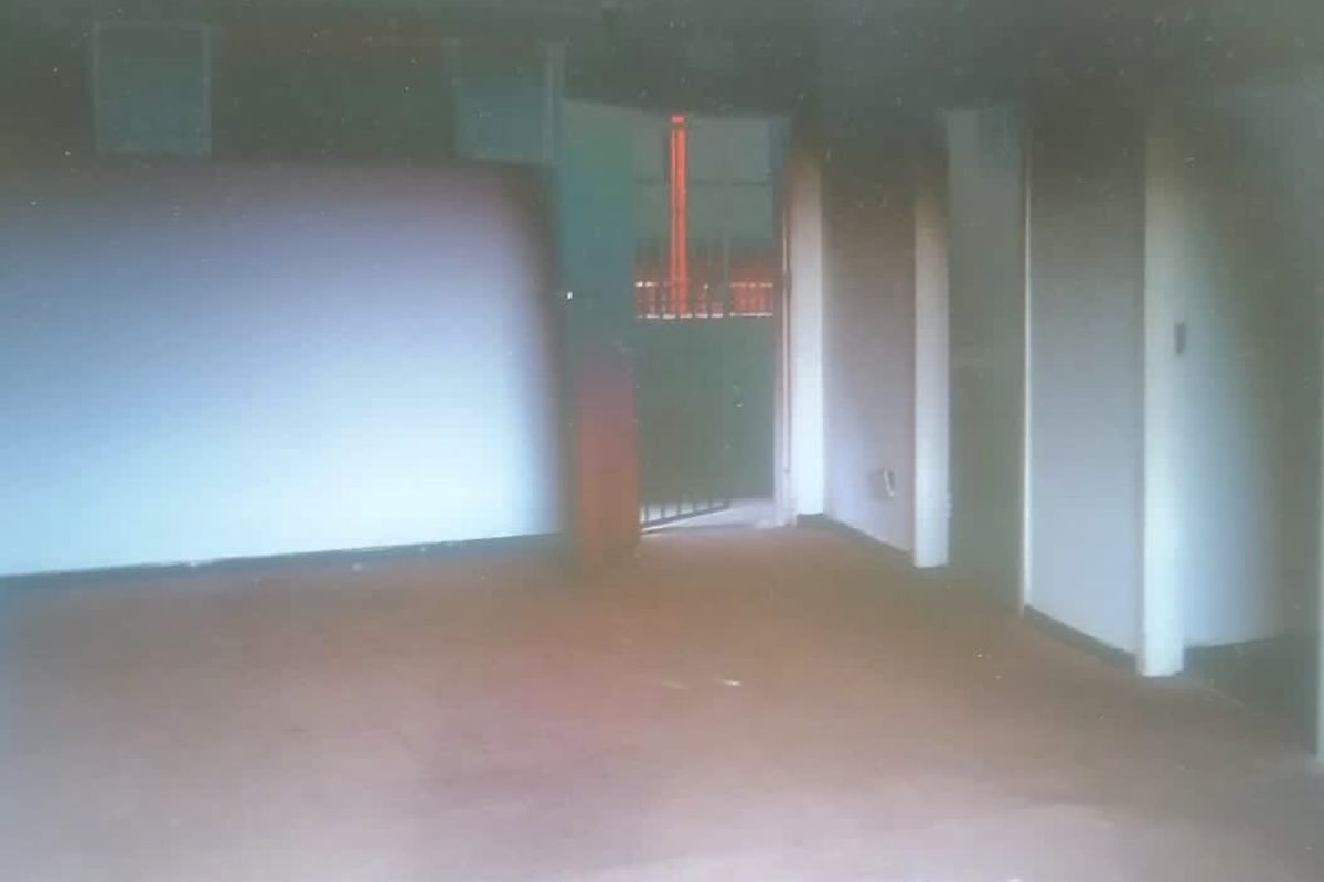 An empty, dimly lit interior space with worn flooring, offering a blank canvas for potential renovation and modernization.