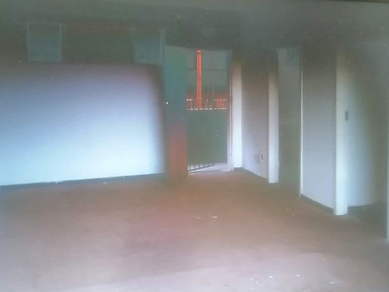 An empty, dimly lit interior space with worn flooring, offering a blank canvas for potential renovation and modernization.