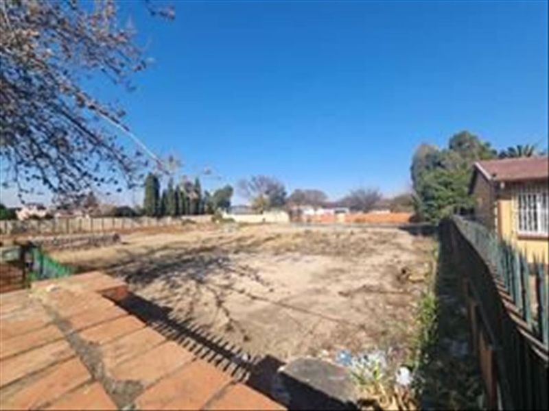 A vacant residential plot featuring a paved patio area and perimeter fencing, offering a blank canvas for future development or landscaping.