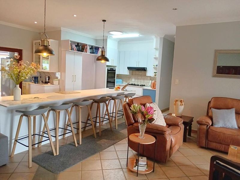 Spacious open-plan living area featuring a modern kitchen with a central island, built-in appliances, and tiled flooring throughout.
