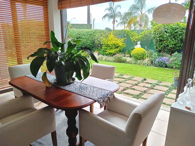 A bright covered patio area featuring tiled flooring and large sliding glass doors that open directly onto a landscaped garden.
